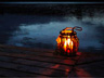 A candle lit lamp on the decking of the boathouse over looking the river at night