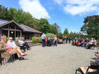 A group of freinds in the walled garden. being served food. listening to live music