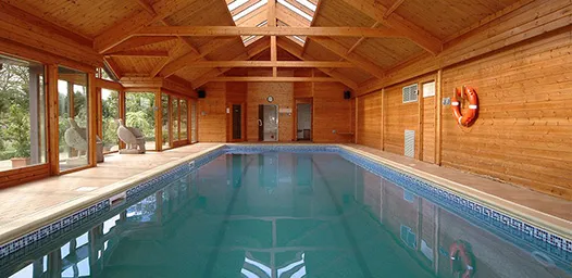 Luscious blue, indoor heated swimming pool, vaulted wooden ceiling with sky lights.